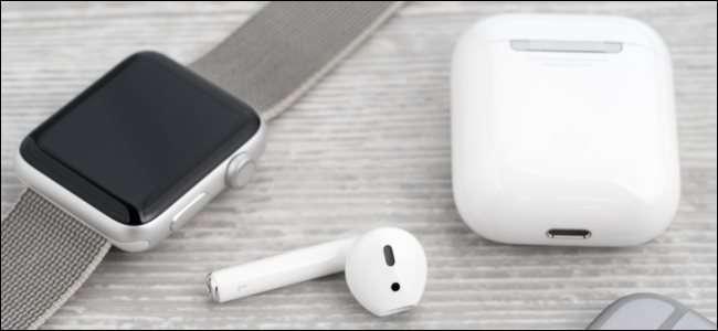 AirPods y su estuche de carga junto a un Apple Watch.