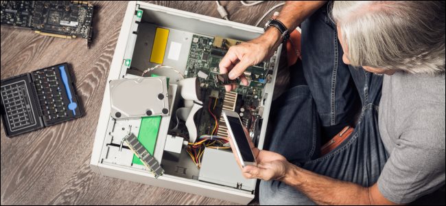 Un hombre montando una computadora de escritorio en el suelo.