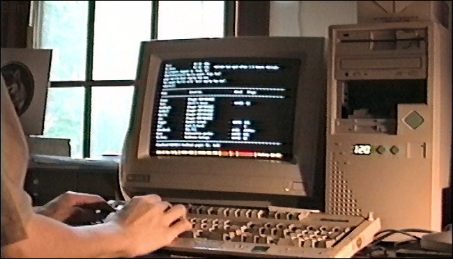 Manos escribiendo en el teclado de una computadora vintage, con un MUSH en la pantalla.