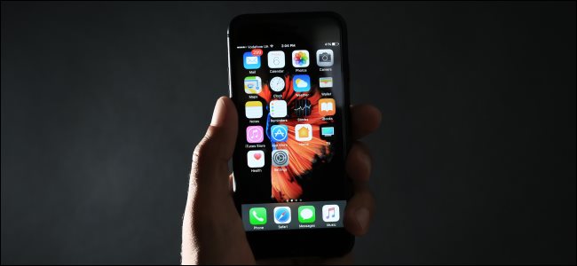 Una mano que sostiene un iPhone negro en la oscuridad.