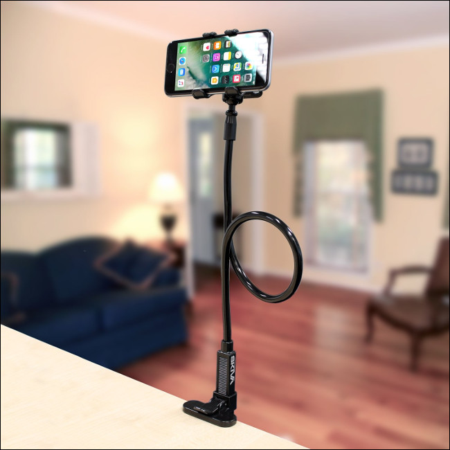 Un iPhone en el soporte con clip para teléfono celular de brazo largo flexible Skiva fijado a una encimera.