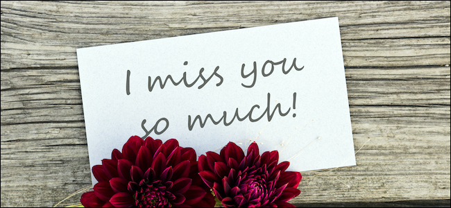 "Te extraño mucho" escrito en un cartel junto a las flores