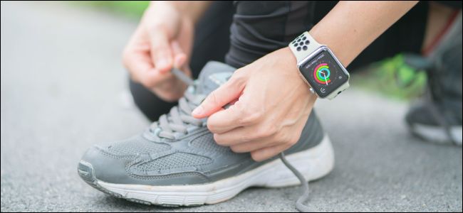 Una persona atando los cordones de los zapatos y usando un Apple Watch.