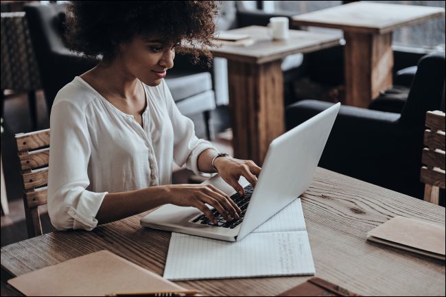 Una mujer sonriente escribiendo en una computadora portátil.