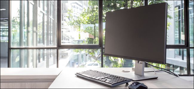 Un monitor de computadora de escritorio, teclado y mouse sobre un escritorio.