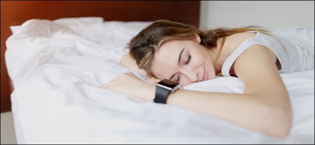 Una mujer durmiendo mientras usa un reloj inteligente.