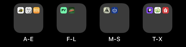 Cuatro carpetas en una pantalla de inicio de iOS etiquetadas alfabéticamente.