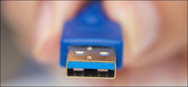 Un hombre que sostiene un conector USB tipo A con el interior azul.