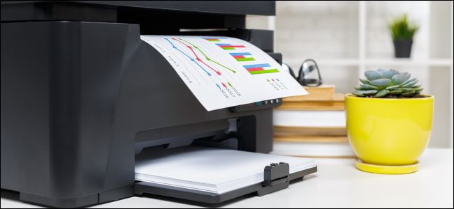 Una impresora sentada en un escritorio, imprimiendo una hoja de papel con un gráfico de barras.