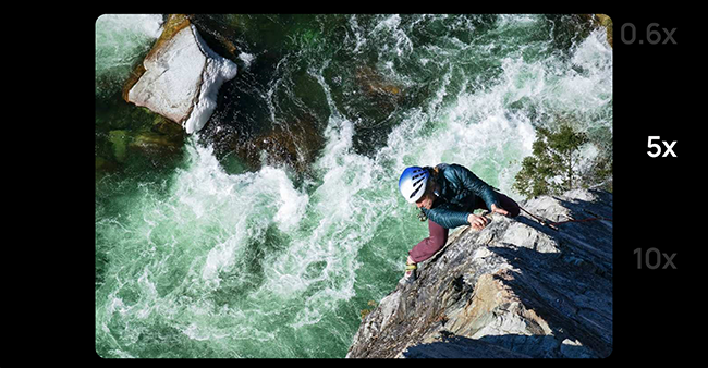 Toma de zoom de un hombre con una cuerda trepando por las rocas junto a un río torrencial. 