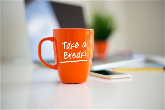 Una taza de café de color naranja con "¡Toma un descanso!"  impreso en él.