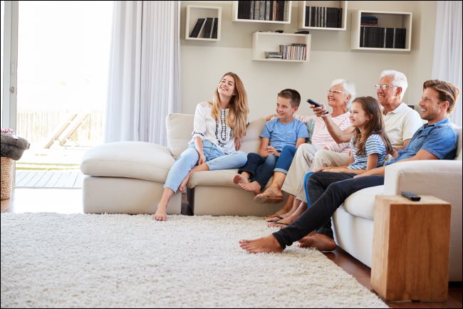 Una familia sentada en un sofá viendo la televisión.