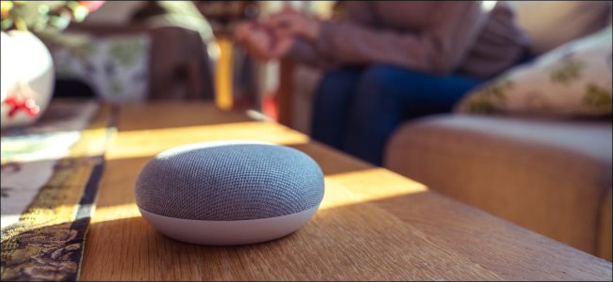 Altavoz inteligente sentado en una mesa con una persona al fondo.