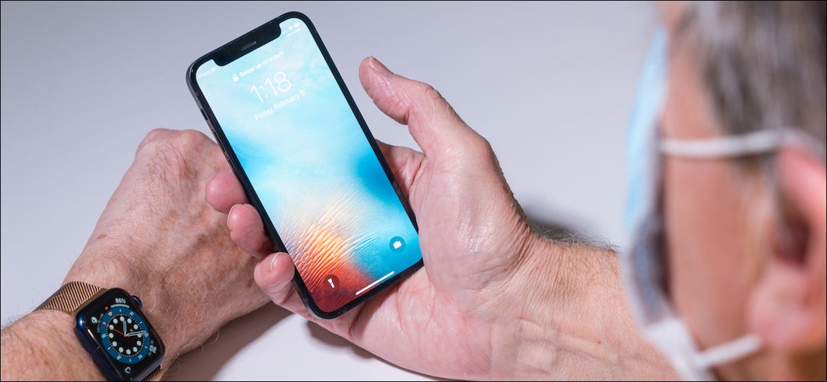 Persona que desbloquea su iPhone mientras usa una máscara