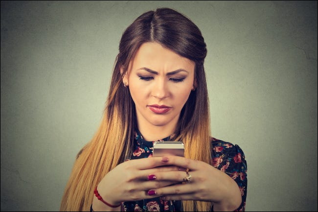 Una mujer infeliz mirando un teléfono inteligente.