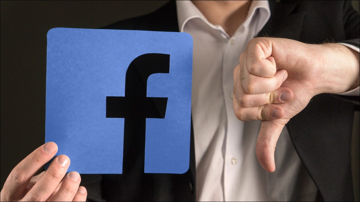 Un hombre dando un pulgar hacia abajo a un logotipo de Facebook.