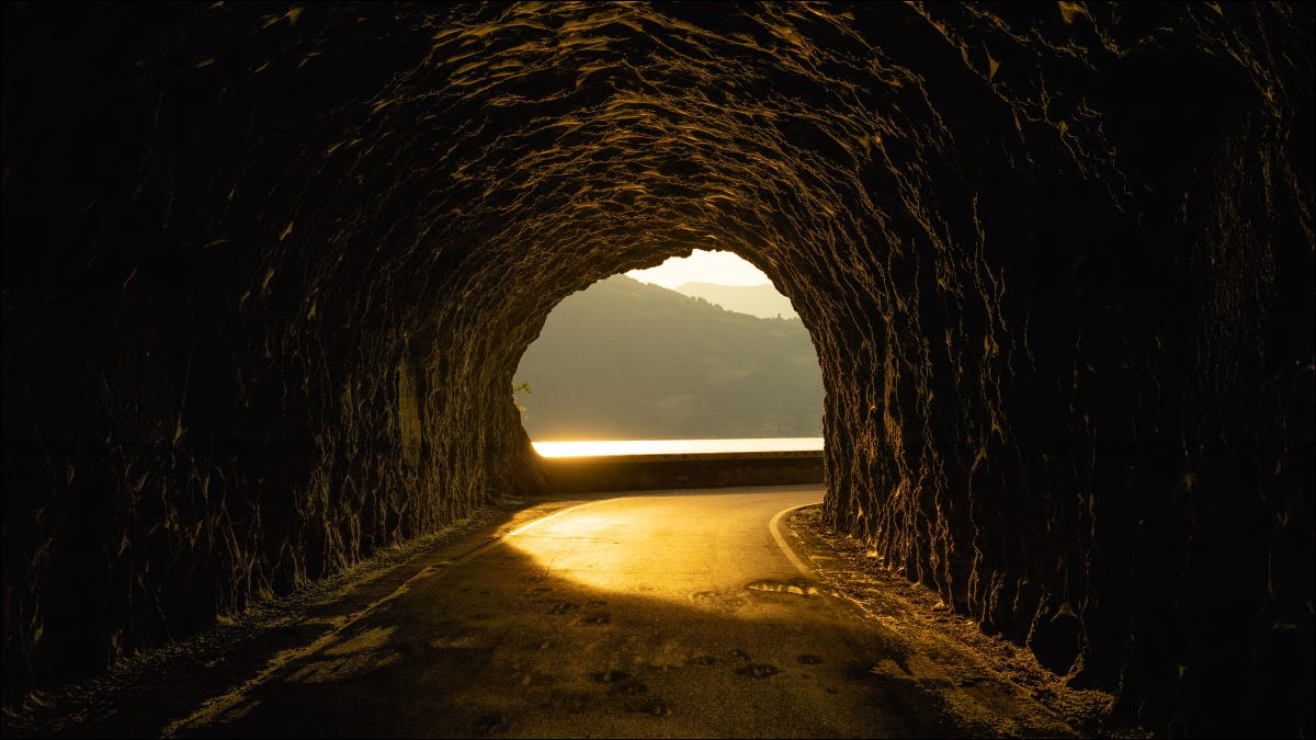 Un túnel rocoso con una puesta de sol al otro lado.