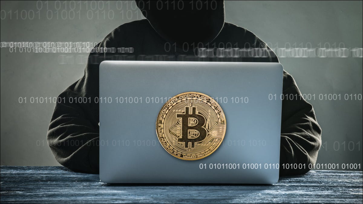 Un "hacker" anónimo estilizado que usa una computadora portátil con una ilustración de Bitcoin.