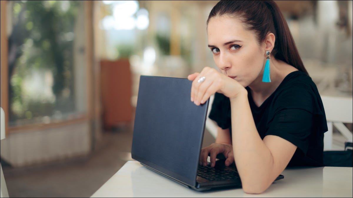 Una mujer preocupada protegiendo una computadora portátil.