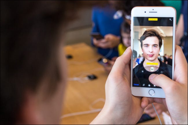 Primer plano de la cara de un hombre reflejada en él en un iPhone con modo vertical
