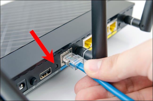Flecha roja que apunta al botón de reinicio en un enrutador de red doméstica