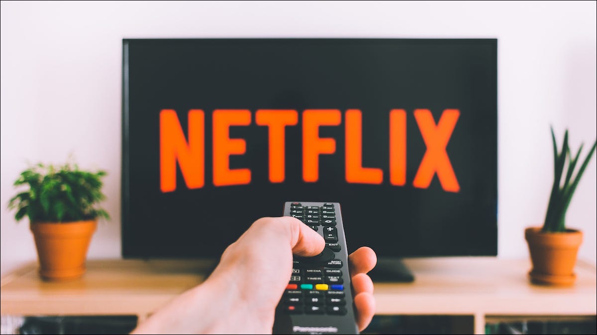 Persona apuntando con un control remoto hacia un televisor con el logotipo de Netflix