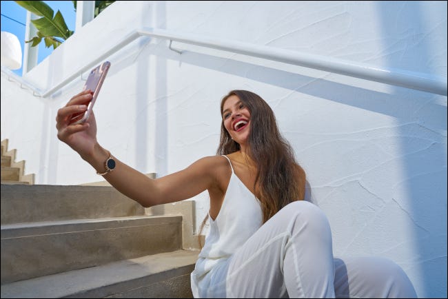 Joven latina sonriendo y mirando hacia arriba para tomar un selfie