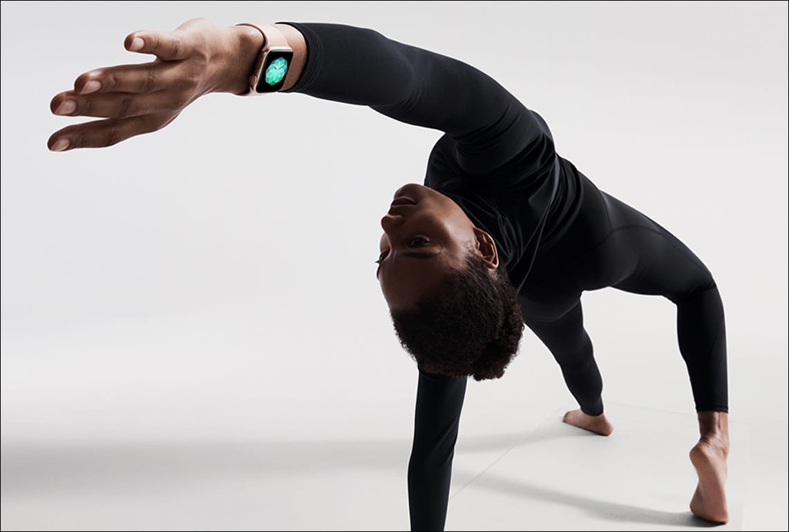 persona que lleva un reloj de manzana mientras hace yoga