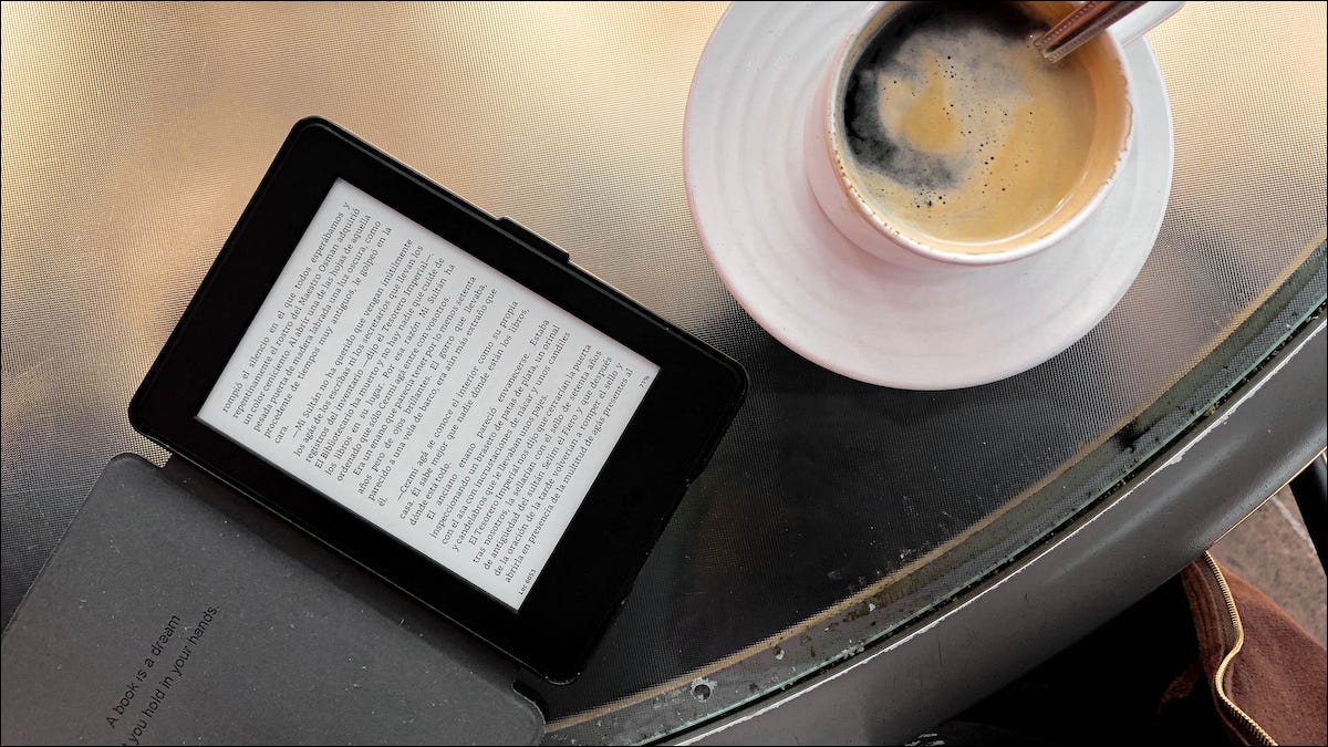Kindle acostado sobre una tableta junto a una taza de café