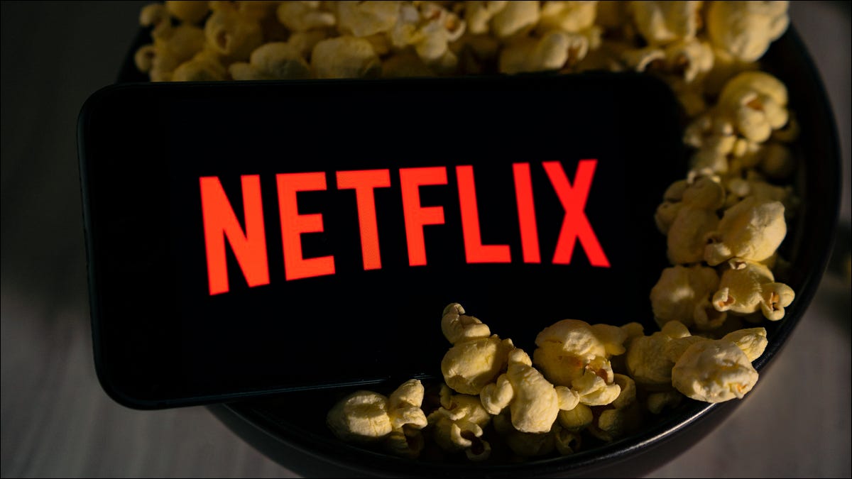 Logotipo de Netflix en un teléfono inteligente sentado en un tazón de palomitas de maíz