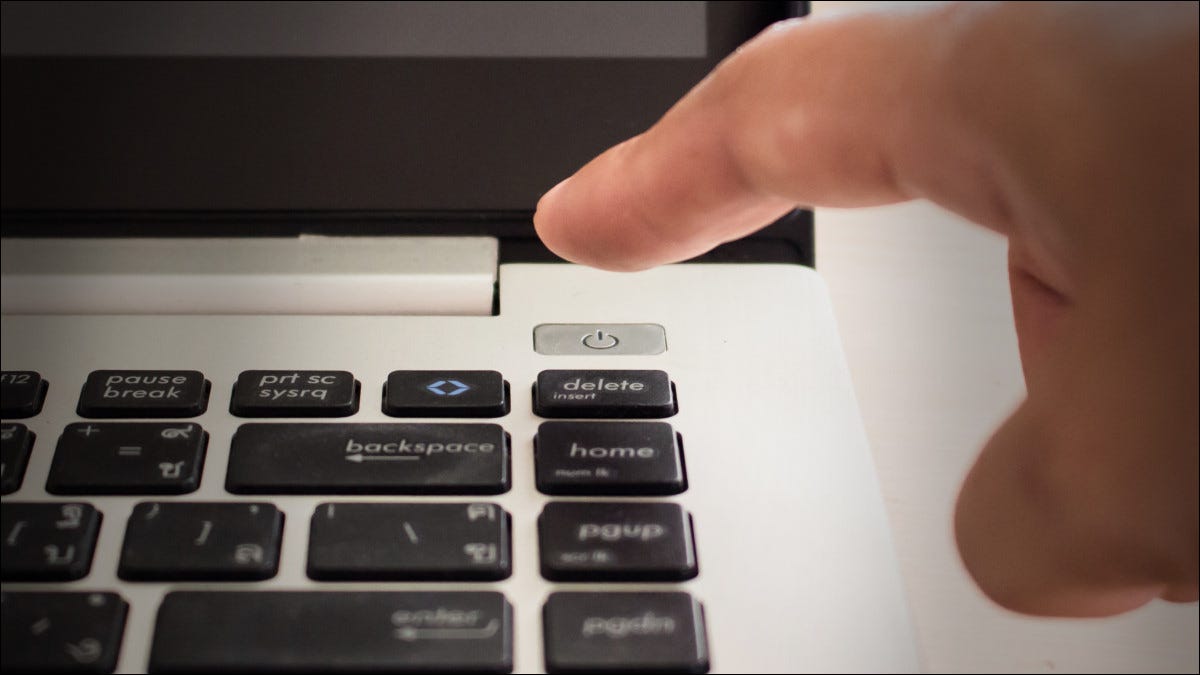 Un dedo a punto de presionar el botón de encendido de una computadora portátil.