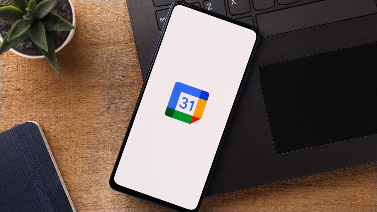 Teléfono inteligente en la parte superior de una computadora portátil con el logotipo de Google Calendar mostrado