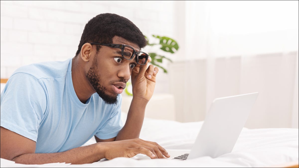 Hombre levantando gafas y mirando consternado a la pantalla de un portátil