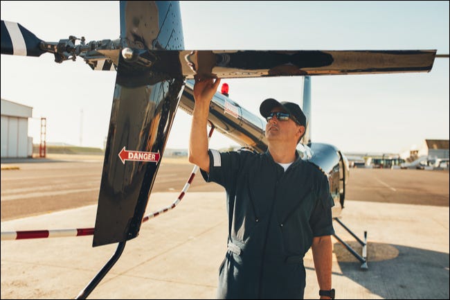 Un piloto examina el rotor de cola de un helicóptero.