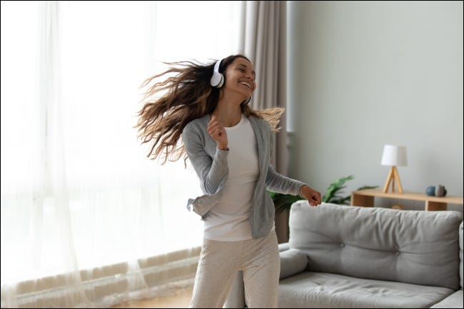 Mujer joven bailando y escuchando música en auriculares.