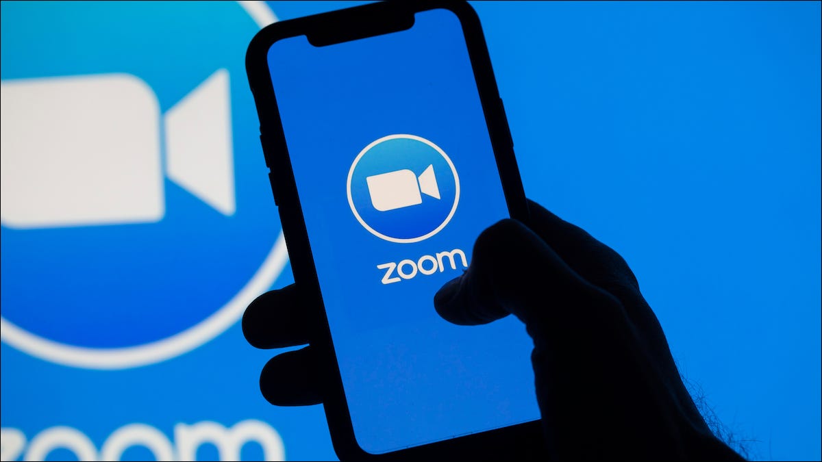 Logotipo de zoom en un teléfono inteligente y un monitor de computadora