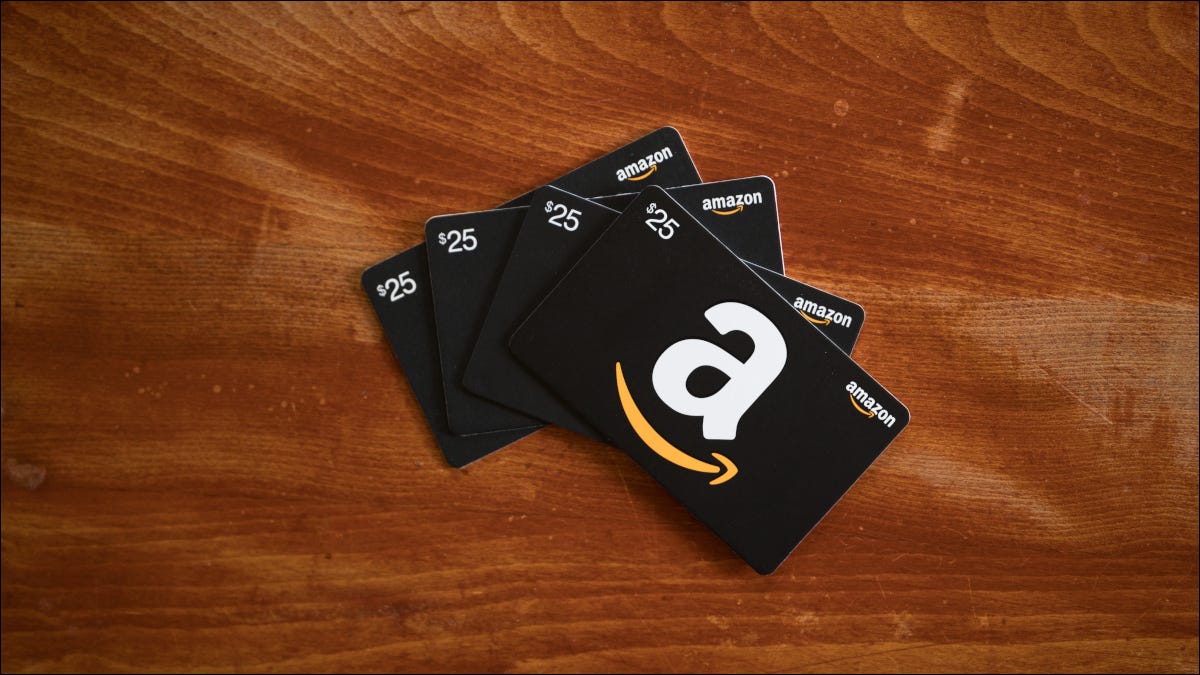 Cuatro tarjetas de regalo de Amazon sobre una superficie de madera
