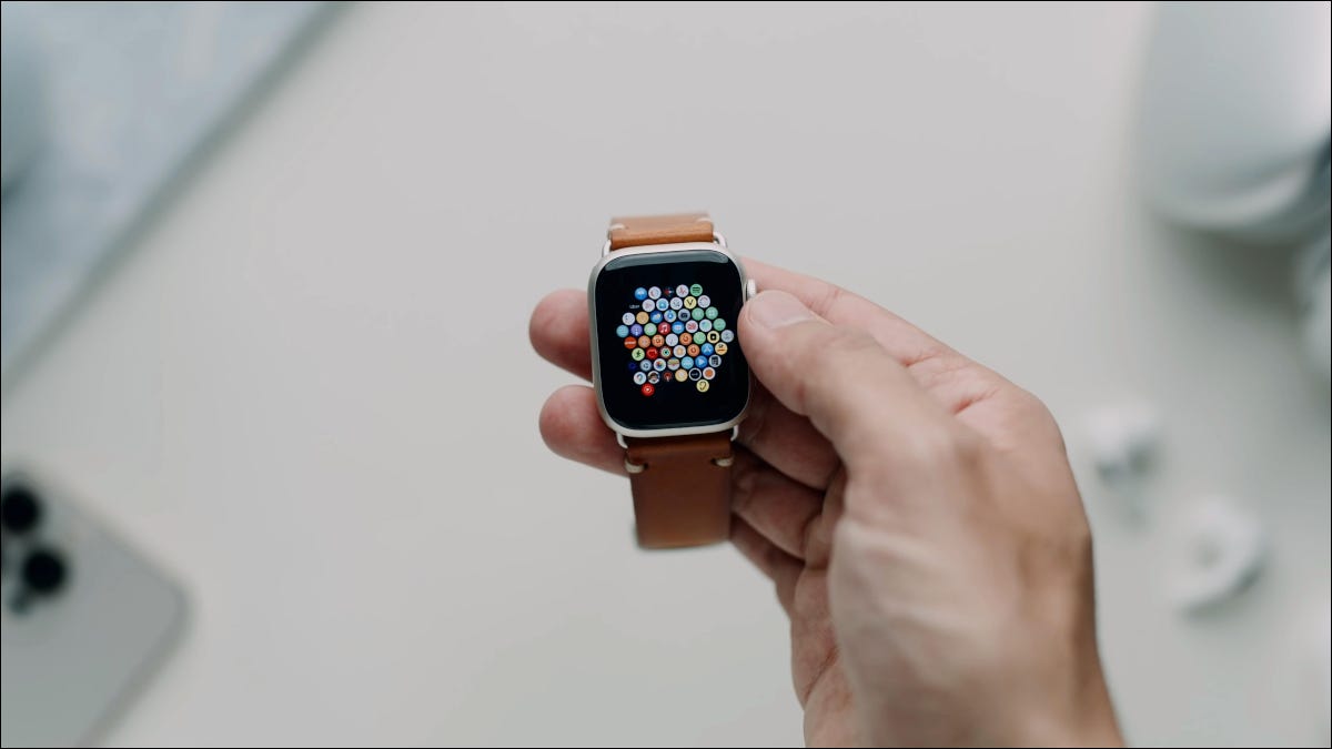 Mano que sostiene un Apple Watch Series 7 con una correa de cuero.