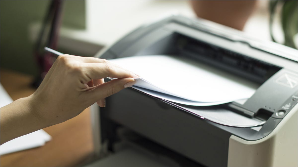 Person, die Papier in einen Laserdrucker einlegt