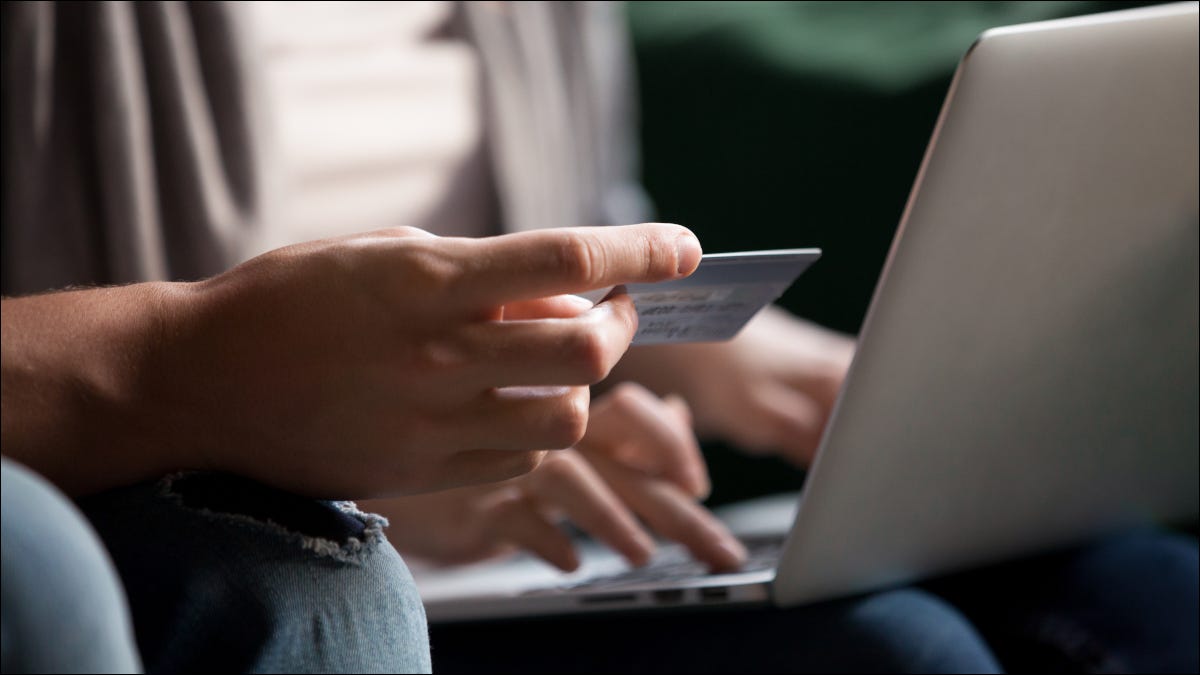 Par de compras en línea con un portátil y sosteniendo una tarjeta de crédito