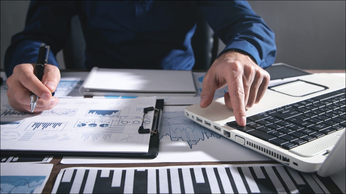 Primer plano de documentos financieros repartidos en un escritorio junto a una computadora portátil