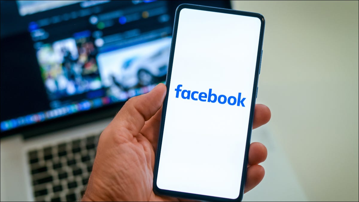 Logotipo de Facebook en un teléfono inteligente sobre una computadora portátil que muestra el perfil de Facebook
