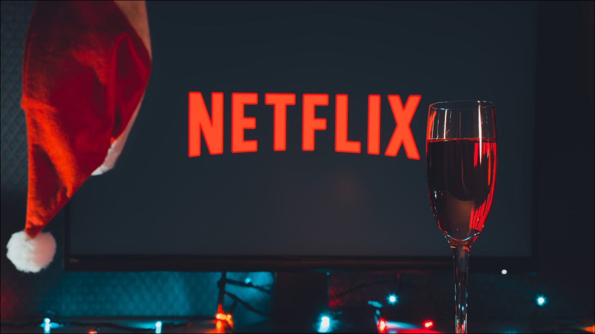 Logotipo de Netflix en una pantalla de TV con un gorro de Papá Noel y copa de champán