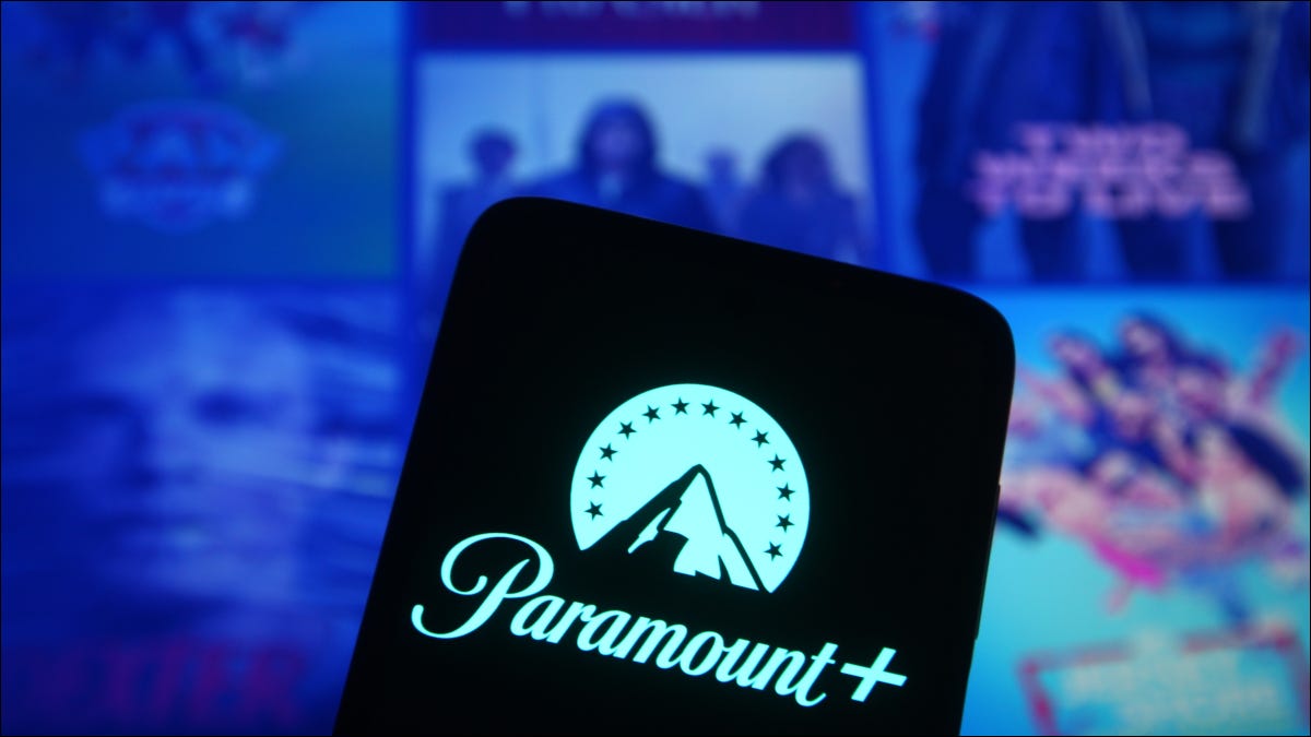 Logotipo de Paramount + en un teléfono inteligente frente a varios carteles de medios
