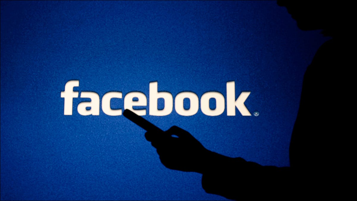 Una figura en sombras frente a un logo de Facebook.