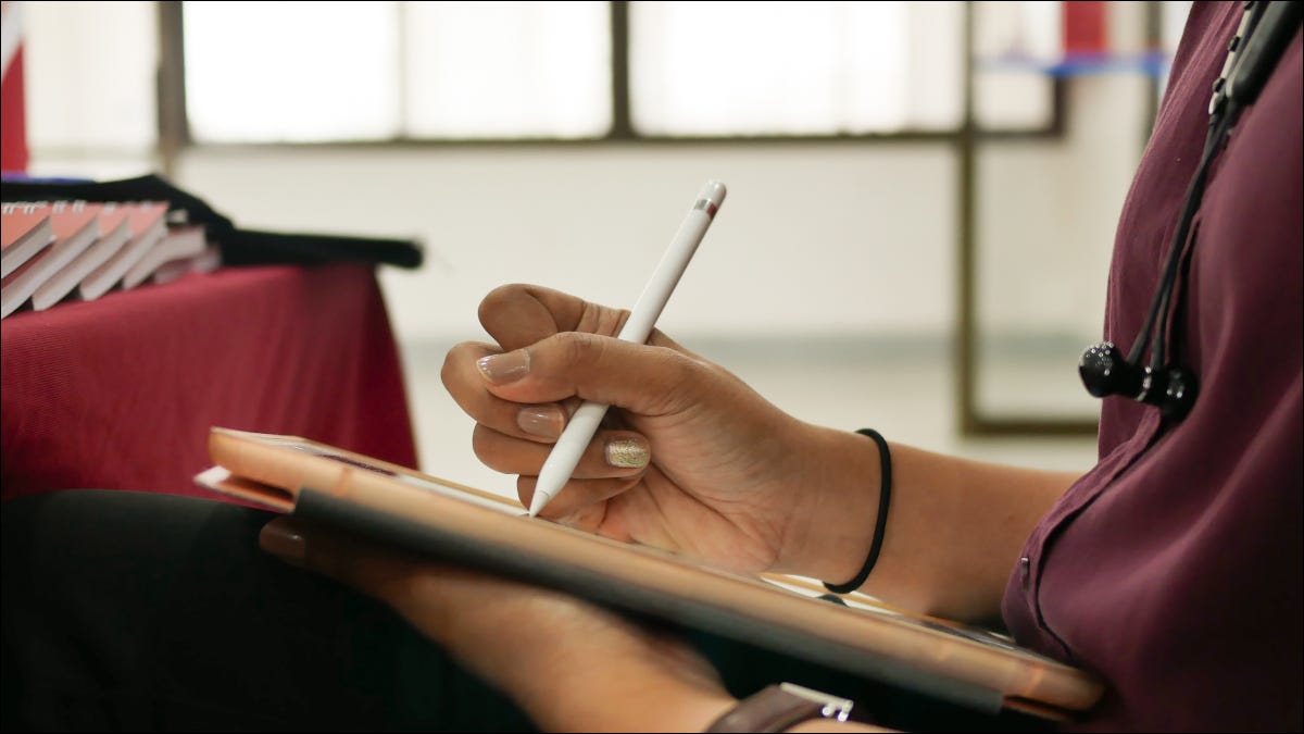 Primer plano de las manos de una mujer dibujando en una tableta con un lápiz