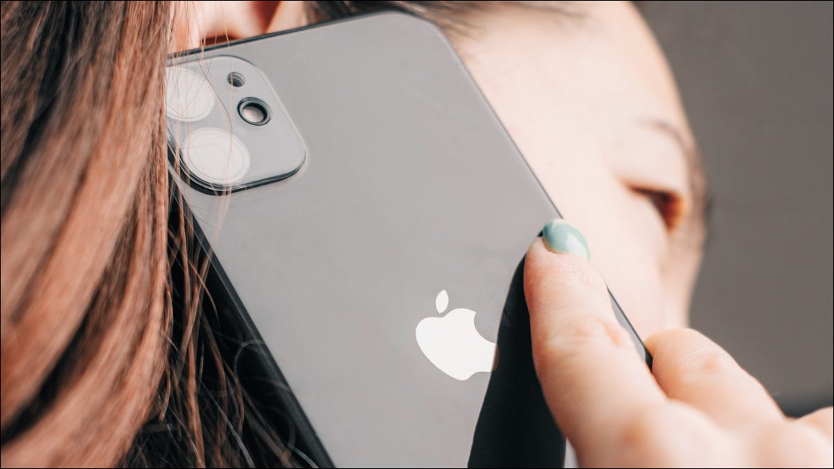 Primer plano de un iPhone 11 negro pegado a la oreja de una mujer