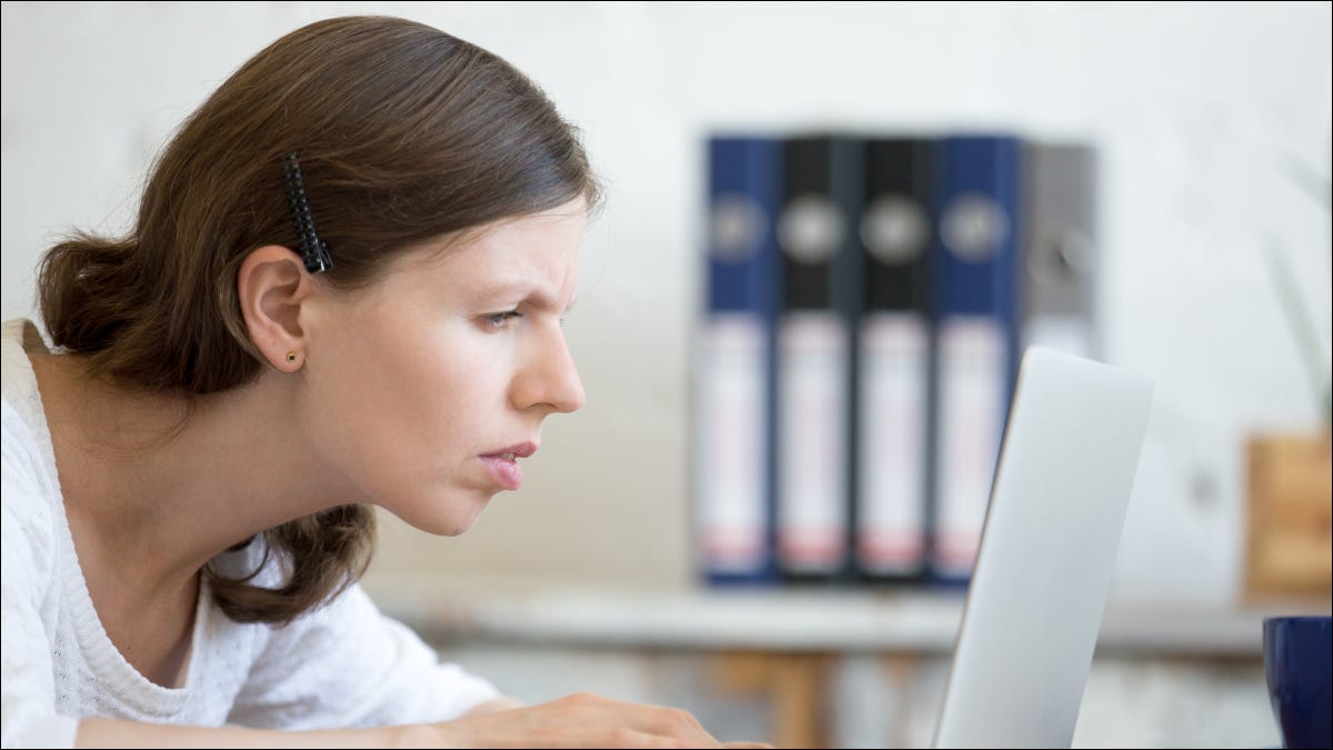 Mujer mirando con una expresión estresada o enfocada en la pantalla de un portátil