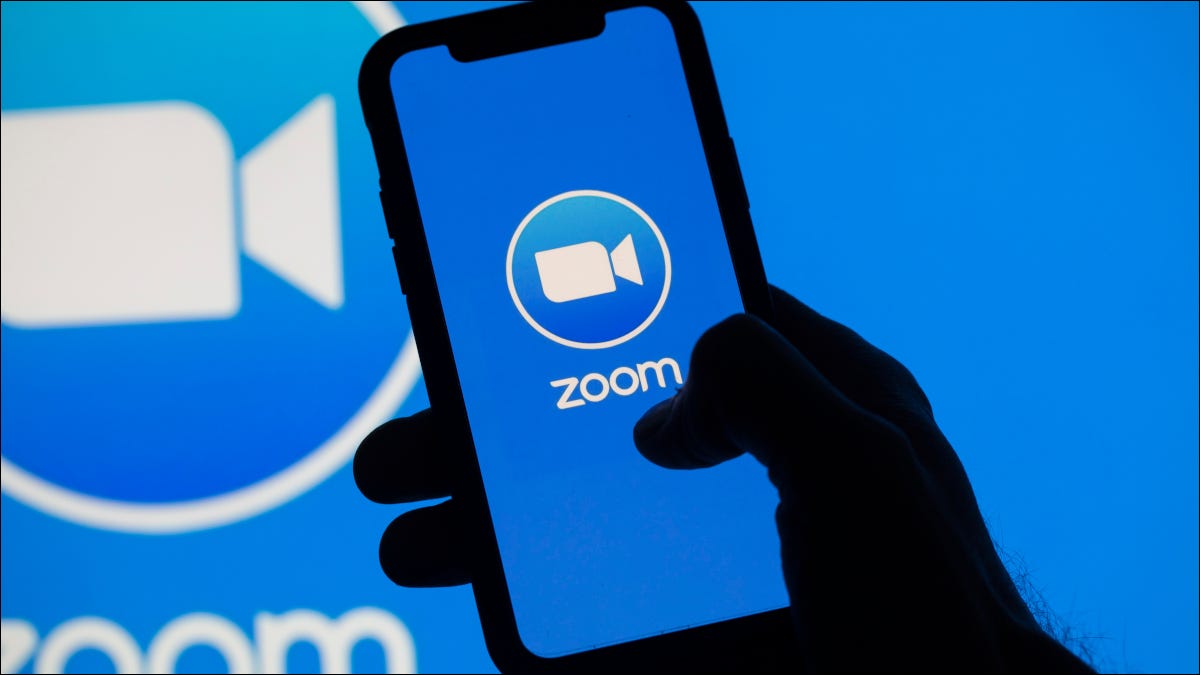 Smartphone que muestra el logotipo de Zoom sobre un fondo de logotipo de Zoom más grande