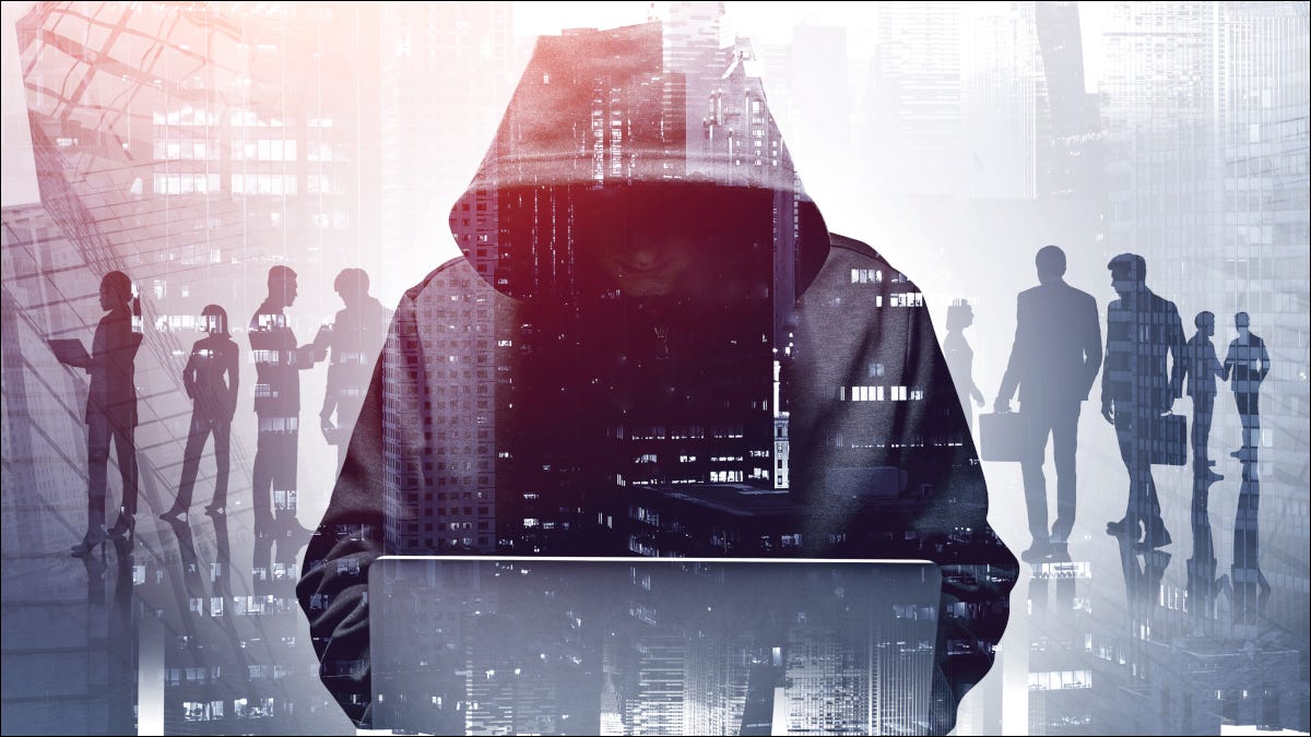Un hacker anónimo con una sudadera con capucha, agachado sobre una computadora portátil.